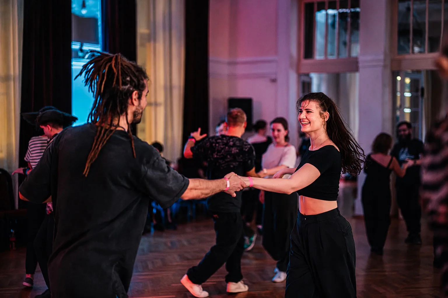 Uśmiechnięta para tańczy West Coast Swing podczas imprezy